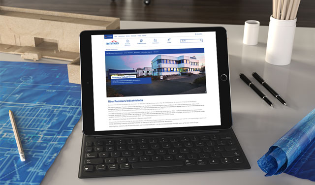 Ein Tablet, auf dem die Remmers Website geöffnet ist, steht auf einem Schreibtisch. Darum herum liegen verschiedene Arbeitsmaterialien.