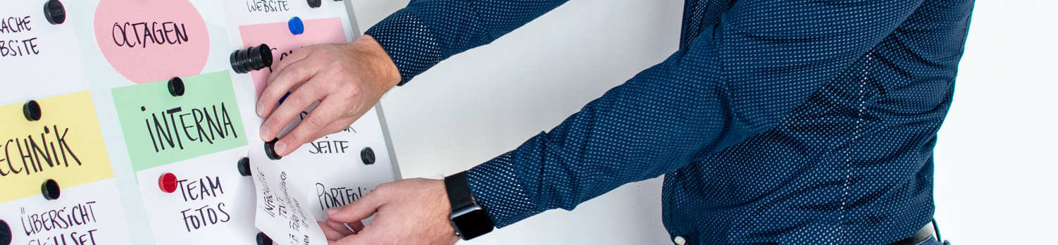 Ein Mitarbeiter hängt Schilder an ein Whiteboard.